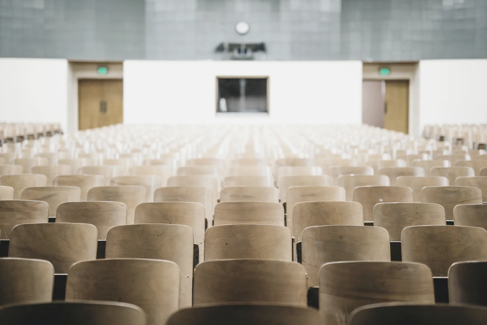 Rows of empty wooden seats in a bright auditorium