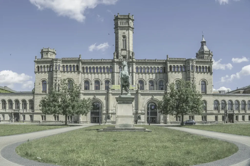 Historic European university building with a statue on its front lawn