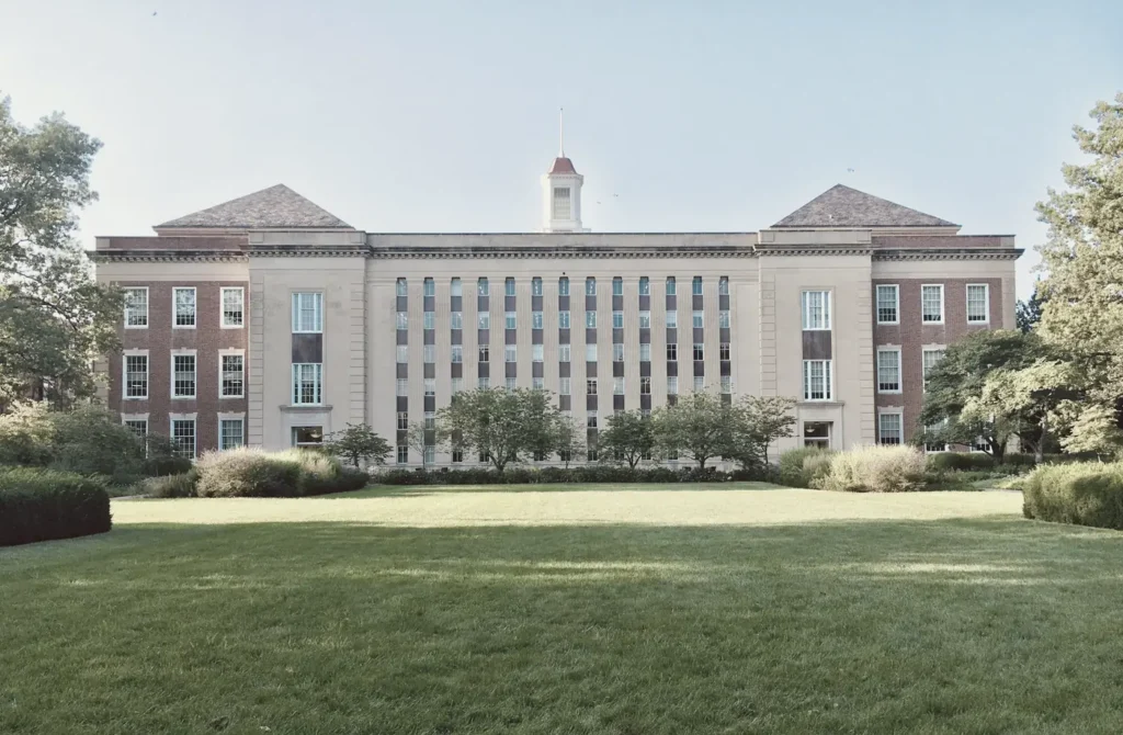 Brick and stone university building across a green campus lawn